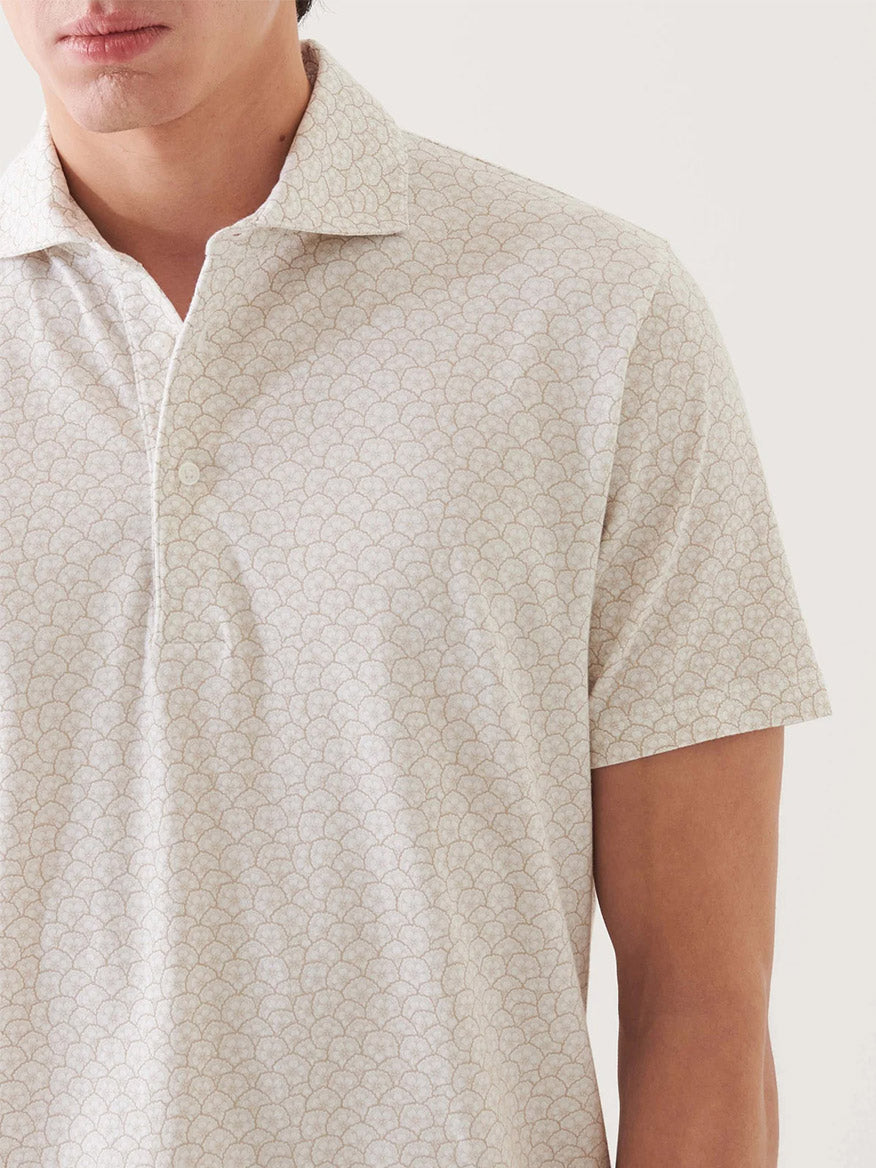 A man wears the Patrick Assaraf Pima Cotton Stretch Printed Polo in Clay, a light-colored, holiday-inspired shirt with a subtle repeating pattern; only his upper torso and part of his face are visible.