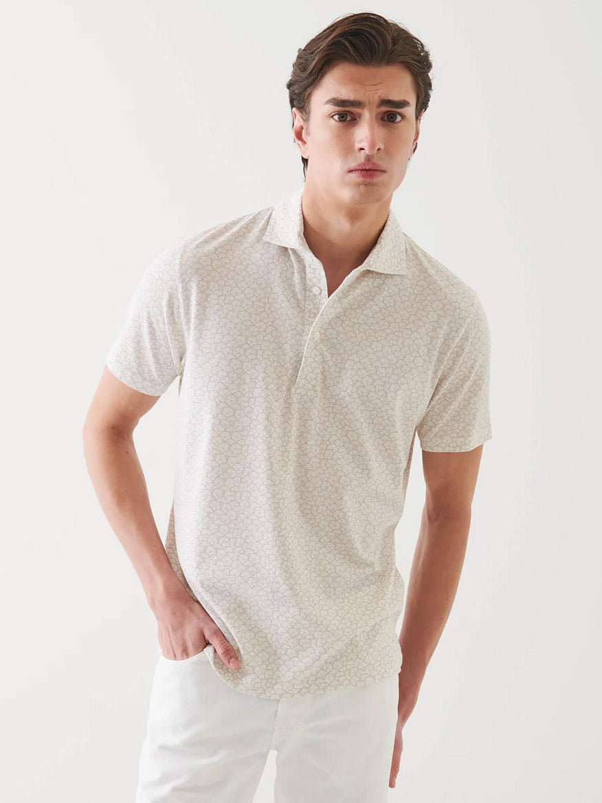 A young man wears the Patrick Assaraf Pima Cotton Stretch Printed Polo in Clay and white pants, standing against a plain white background.