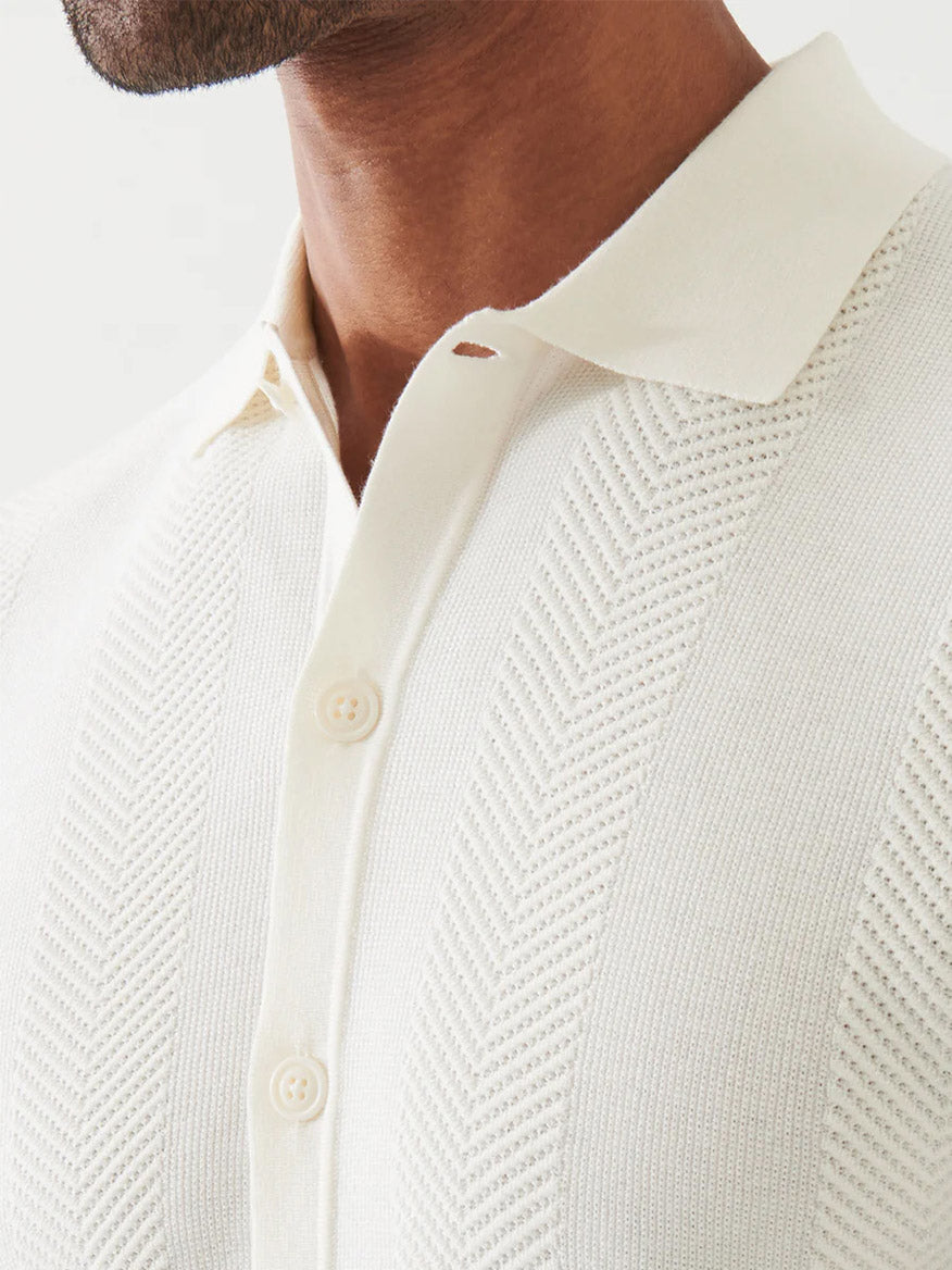Close-up of a person wearing the Patrick Assaraf Cotton Cashmere Blend Knit Shirt in White, featuring a collar and two visible buttons.