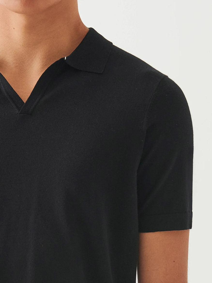 The Patrick Assaraf Cotton Cupro Open Polo in Black—short-sleeved with a sleek open collar—is shown from shoulders to chest against a plain background.