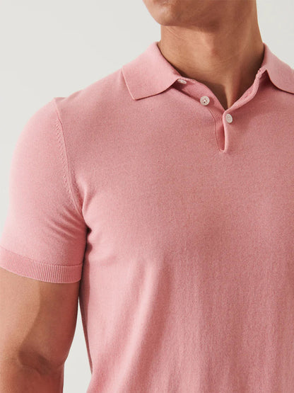 Close-up of a person wearing a Patrick Assaraf Cotton Cupro Polo in Guava with buttoned collar and short sleeves, focusing on the fabric and details around the upper chest and shoulder area.