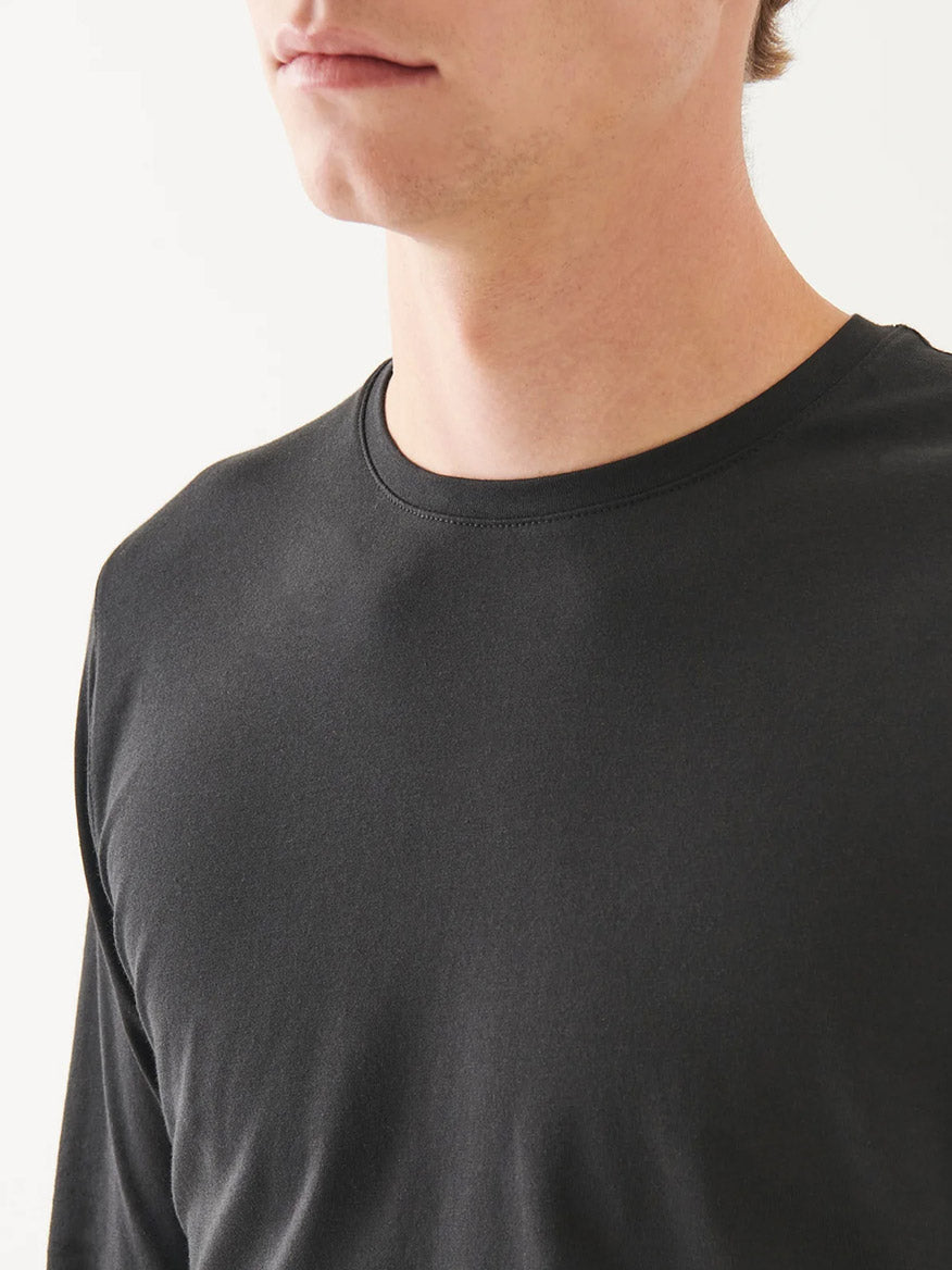 A person wears the Patrick Assaraf Pima Cotton Stretch Long Sleeve T-Shirt in Black, slim fit, shown from the shoulders up against a white background.