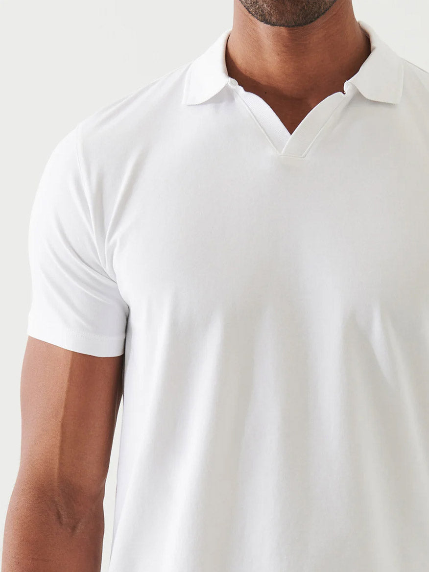 Man wearing the Patrick Assaraf Pima Cotton Stretch Open Polo in White, featuring short sleeves, an open polo collar with a split neckline, shown from shoulders to upper chest against a light background for all-day comfort.