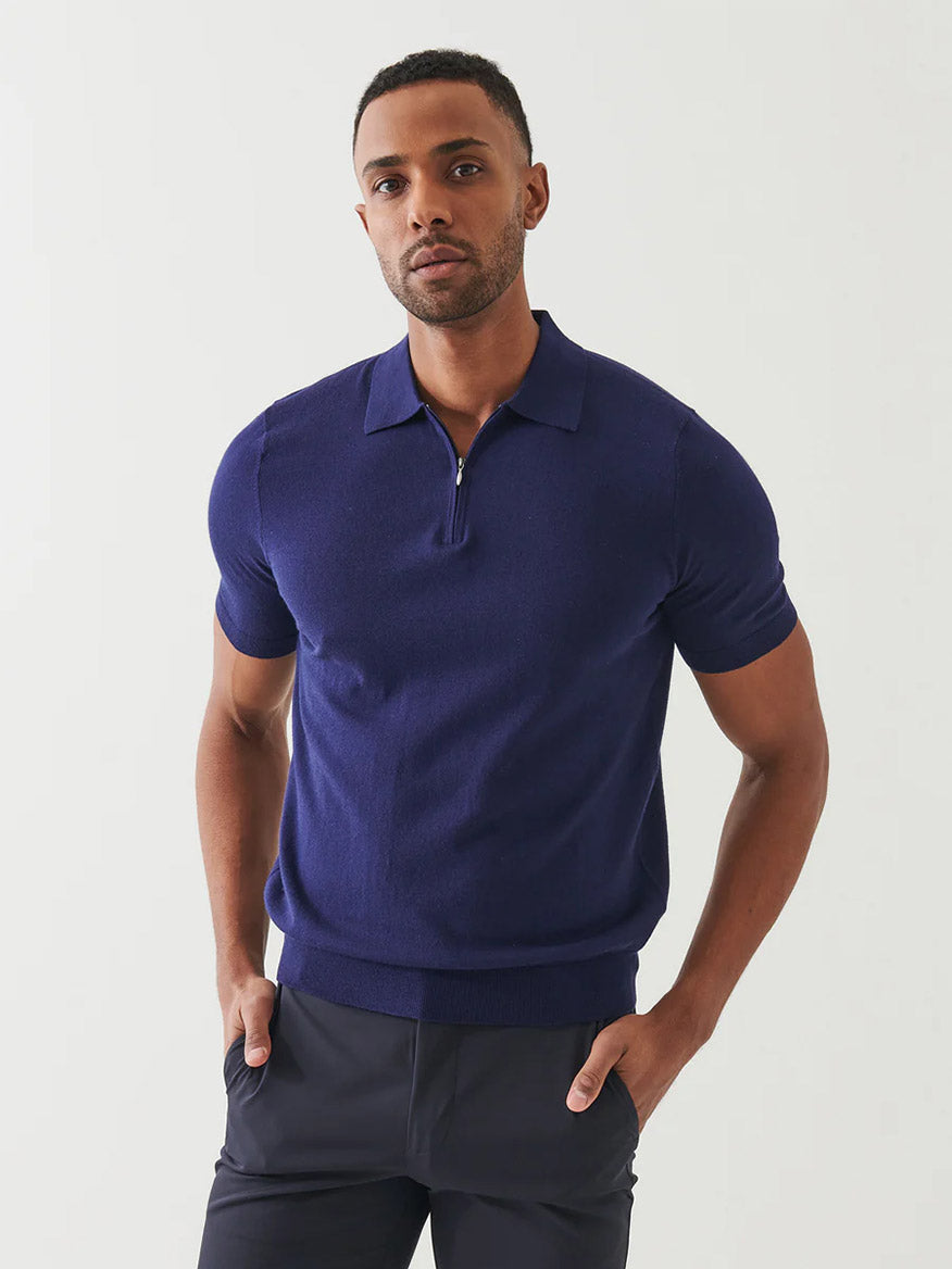 A man stands against a plain light background wearing the Patrick Assaraf Cotton Cashmere Quarter Zip Polo in Navy and dark pants, hands in pockets—an effortless, versatile look.