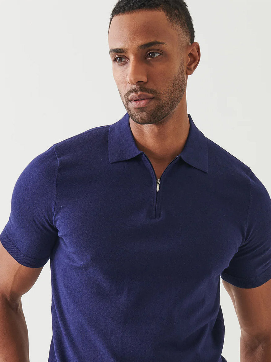 A man wears the Patrick Assaraf Cotton Cashmere Quarter Zip Polo in Navy, featuring short sleeves and a fitted design, standing against a plain light background.