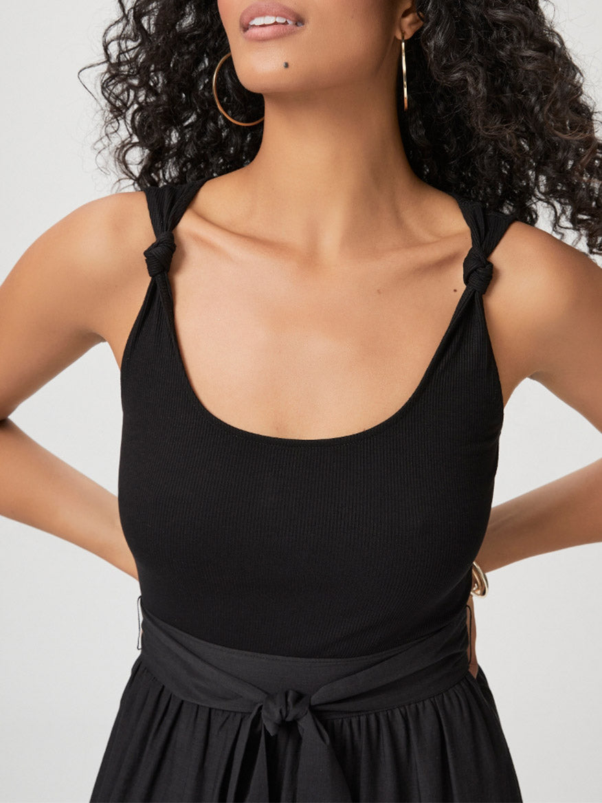 A woman wearing a Paige Samosa Dress in Black with knot details on the straps, focusing on her upper body.