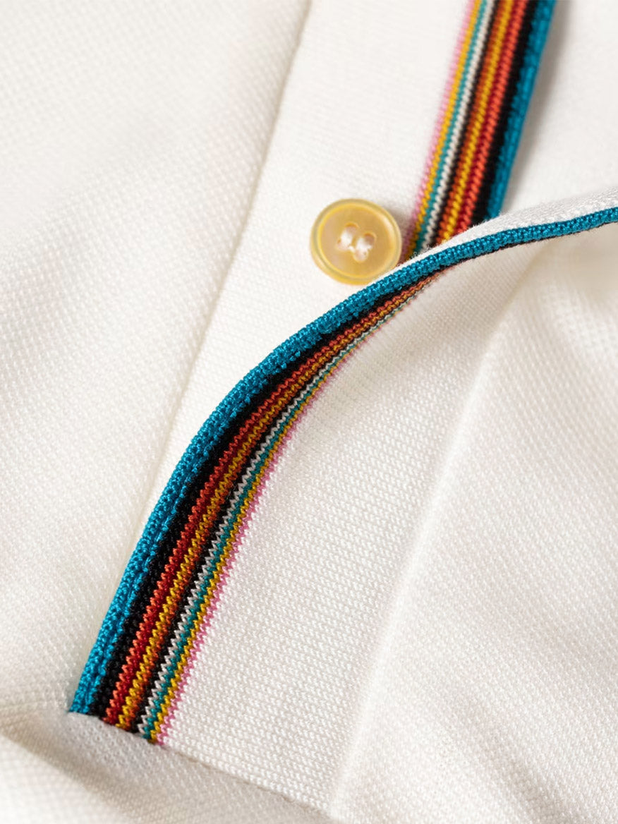 Close-up of the Paul Smith Signature Stripe Trim Polo Shirt in white, featuring a cream textured fabric, yellow button, and Signature Stripe trim along the placket and collar edge.