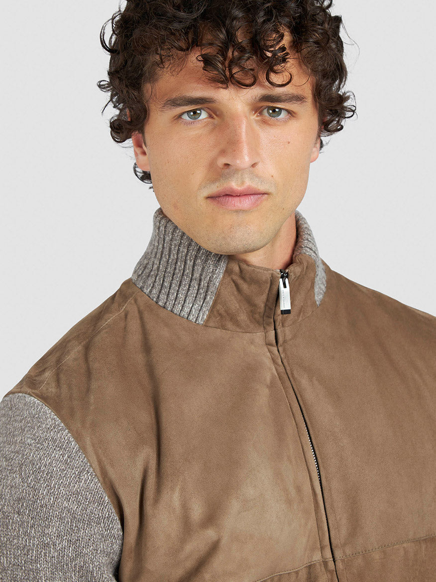 A man with curly brown hair wears the Paul & Shark Hybrid Zip-Up Cardigan in Natural, featuring a suede front and gray wool-cashmere sleeves and collar, as he looks directly at the camera.