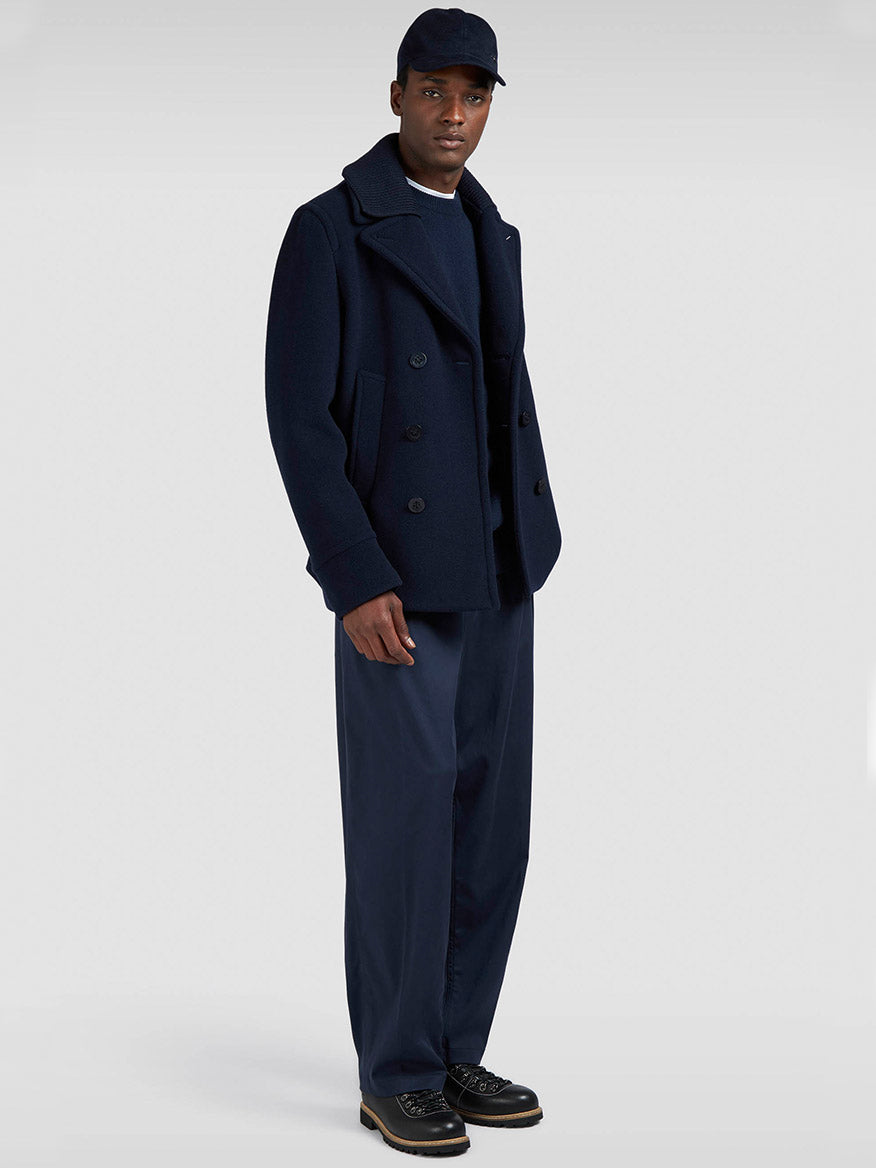 A man wearing the Paul & Shark Peacoat in Wool & Cashmere in Navy, wide-leg navy pants, black shoes, and a navy baseball cap stands against a plain light background.