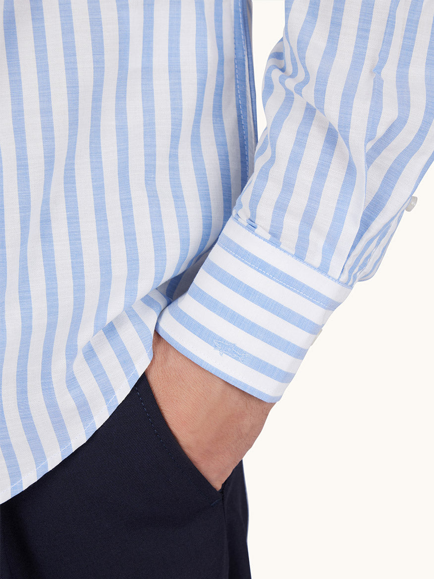 Someone wears the Paul & Shark Cotton Poplin Shirt With Striped Pattern in White/Blue, featuring vertical stripes, a button-down collar, visible sleeve cuff, and has a hand in the pocket of dark pants.
