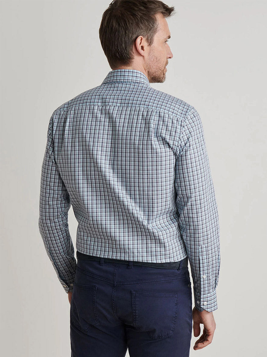 A man stands with his back to the camera, wearing a Peter Millar Abetone Cotton Sport Shirt in Blue Frost and navy pants against a plain background.