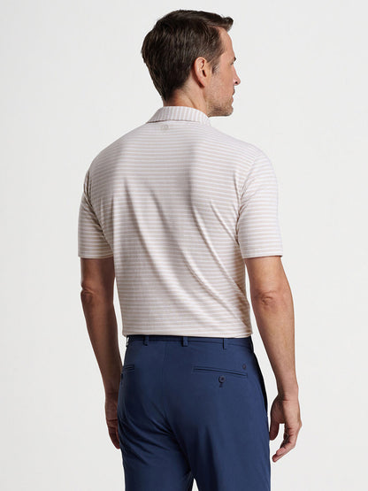 Man standing in a profile view, wearing a Peter Millar Albatross Cotton Blend Piqué Polo in Summer Dunes and blue trousers.