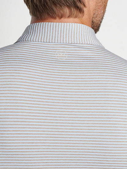 A close-up view of a man's back wearing a striped polo shirt with a visible Peter Millar Ambrose Performance Jersey Polo in Khaki label on the collar.