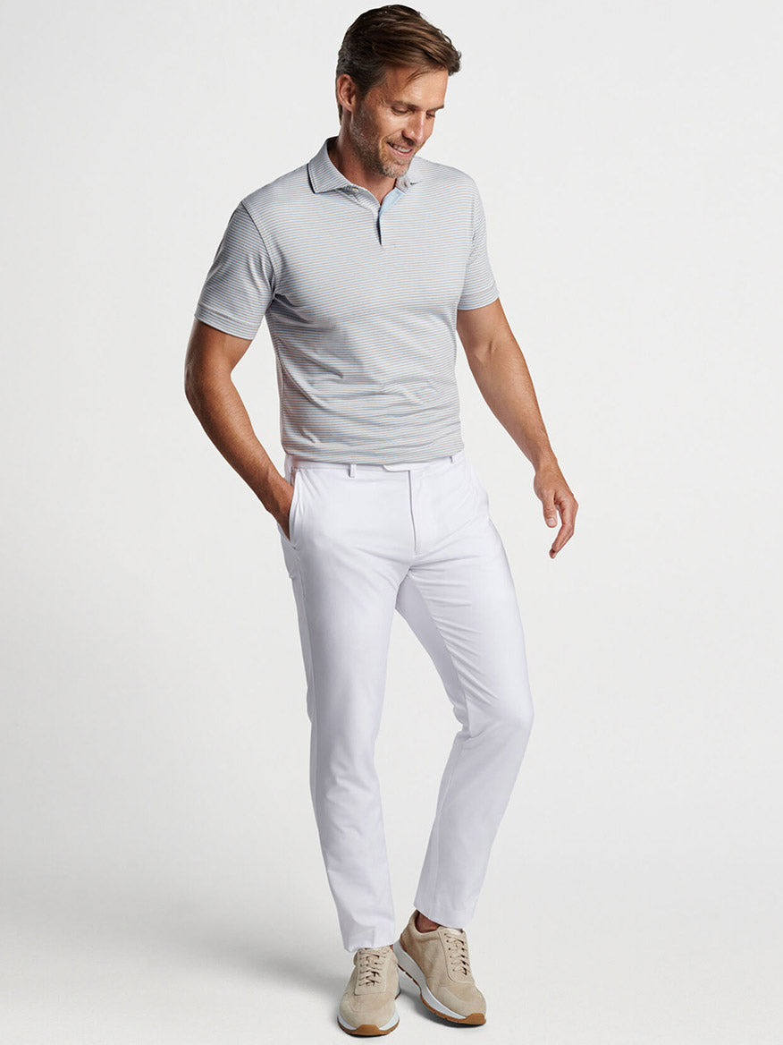 Man in a Peter Millar Ambrose Performance Jersey Polo in Khaki and white pants posing casually.