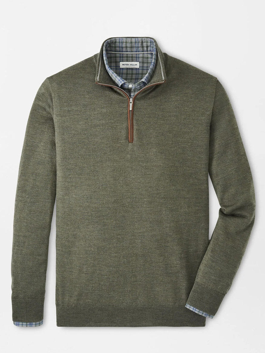 A Peter Millar Autumn Crest Suede Trim Quarter-Zip in Basil, a lightweight olive green sweater with a classic fit, is layered over a blue plaid button-down and displayed neatly on a flat surface.