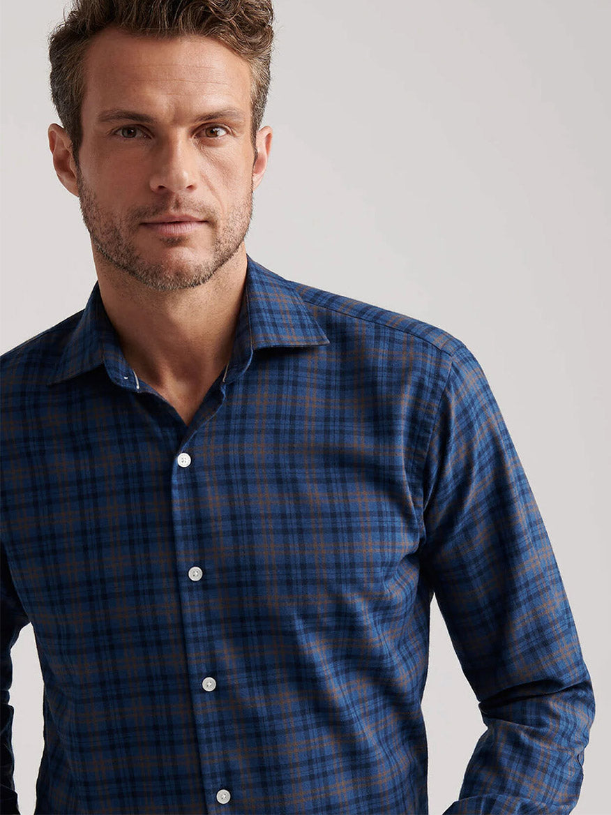 A man wears the Peter Millar Bar Harbor Performance Flannel Sport Shirt in Blue Haze, made from lightweight performance fibers, standing against a plain light background and looking at the camera.