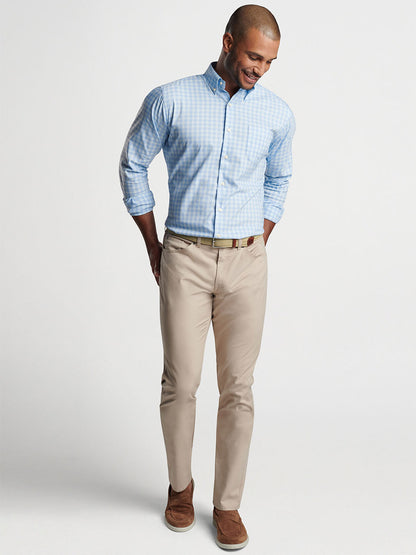 Man in a Peter Millar Bethel Crown Lite Cotton-Stretch Sport Shirt in Cottage Blue and khaki pants smiling and looking downward.