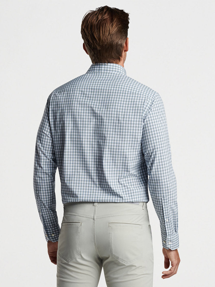 Man viewed from behind wearing a Peter Millar Cole Performance Poplin Sport Shirt Sage Fog with UPF 50+ sun protection and light gray pants, standing against a plain white background.
