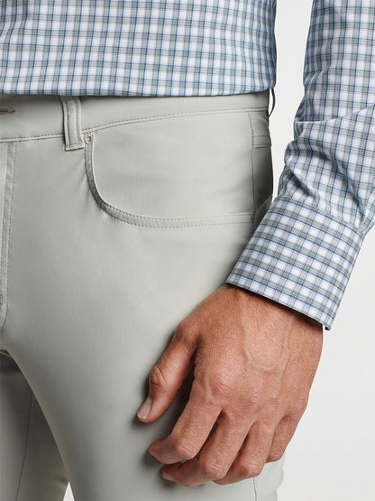 Close-up of a man's hand in his pocket, wearing light gray pants and a Peter Millar Cole Performance Poplin Sport Shirt Sage Fog with UPF 50+ sun protection.