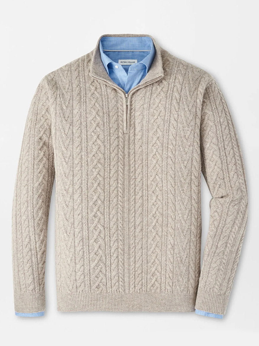 The Peter Millar Crescent Ridge Cable Quarter-Zip Sweater in Light Elm, crafted from blended wool yarn, is styled over a light blue collared shirt and laid flat on a white background.