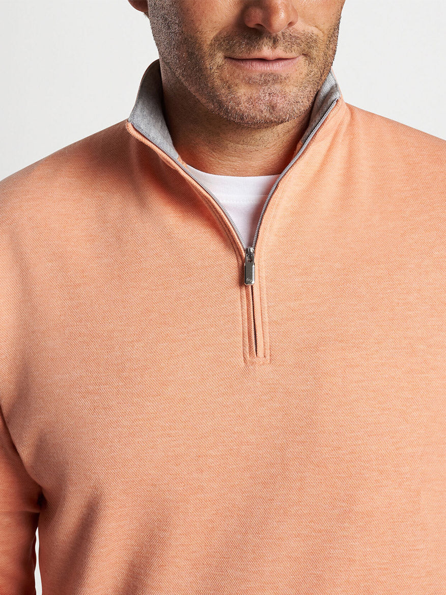 A man wearing a Peter Millar Crown Comfort Pullover in Coral Haze.