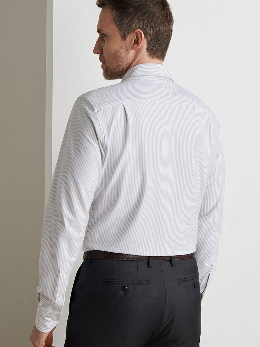 A man stands facing away from the camera, wearing the Peter Millar Excursionist Flex Stripe Sport Shirt in British Grey with black trousers against a plain background.