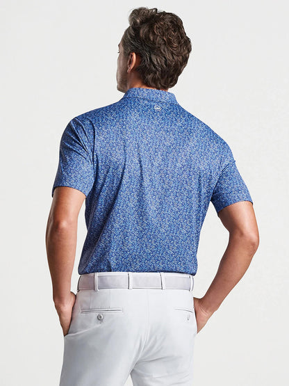 Man from behind wearing a Peter Millar Fields of Carlsbad Performance Jersey Polo in Blue Pearl and white pants.