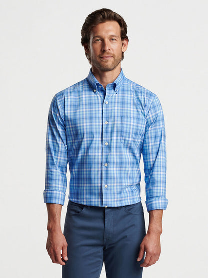 Man in Peter Millar Freeport Crown Lite Cotton-Stretch Sport Shirt in Maritime and gray trousers standing against a white background, hands by his sides, looking at the camera.