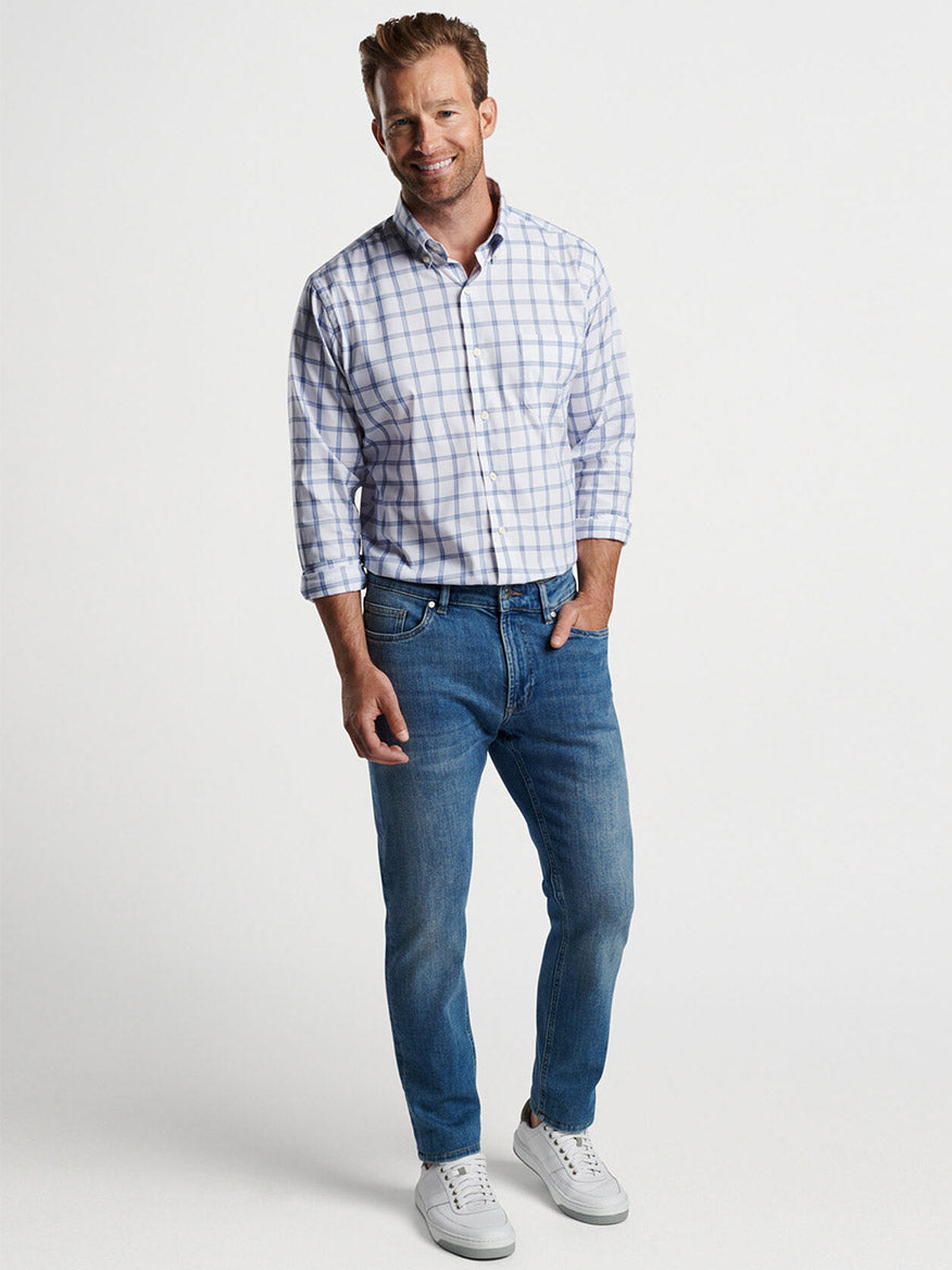 Man posing in a Peter Millar Gorham Crown Lite Cotton-Stretch Sport Shirt in White and jeans with one hand in his pocket.