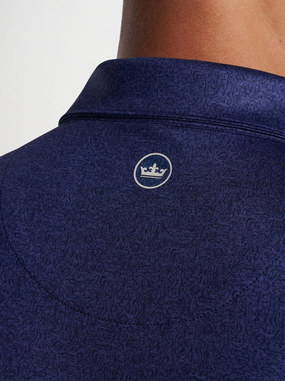 Close-up of a Peter Millar Instrumental Nouveau Performance Jersey Polo in Navy with a textured pattern and a small logo on the back collar.