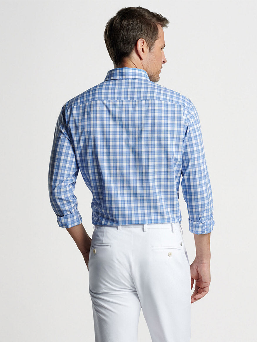 Man wearing a Peter Millar Joplin Performance Poplin Sport Shirt in Regatta Blue with UPF 50+ sun protection and white pants, viewed from behind.