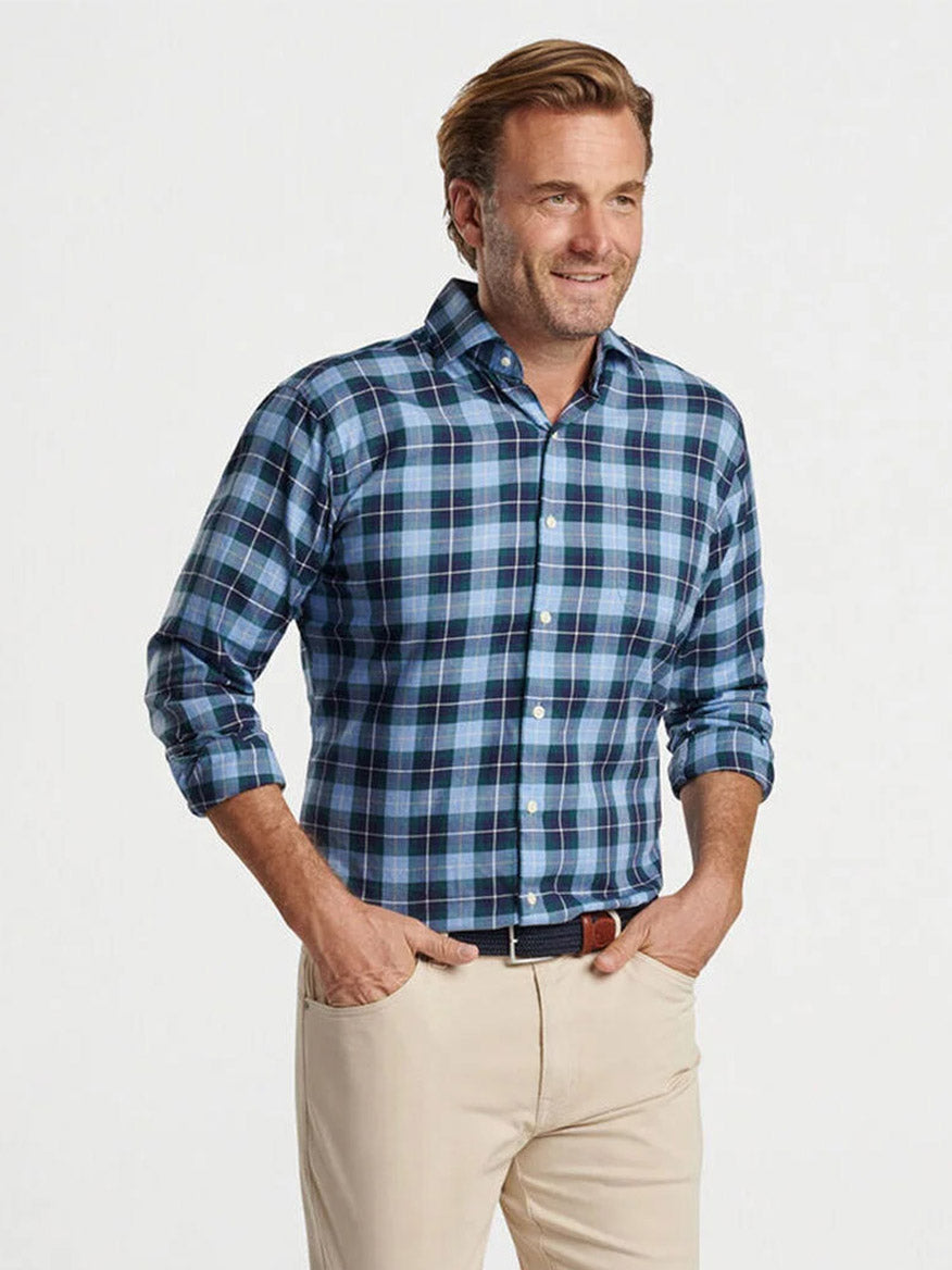 A man wearing the Peter Millar Langley Summer Soft Cotton Sport Shirt in Cottage Blue pairs it with beige pants against a plain background.