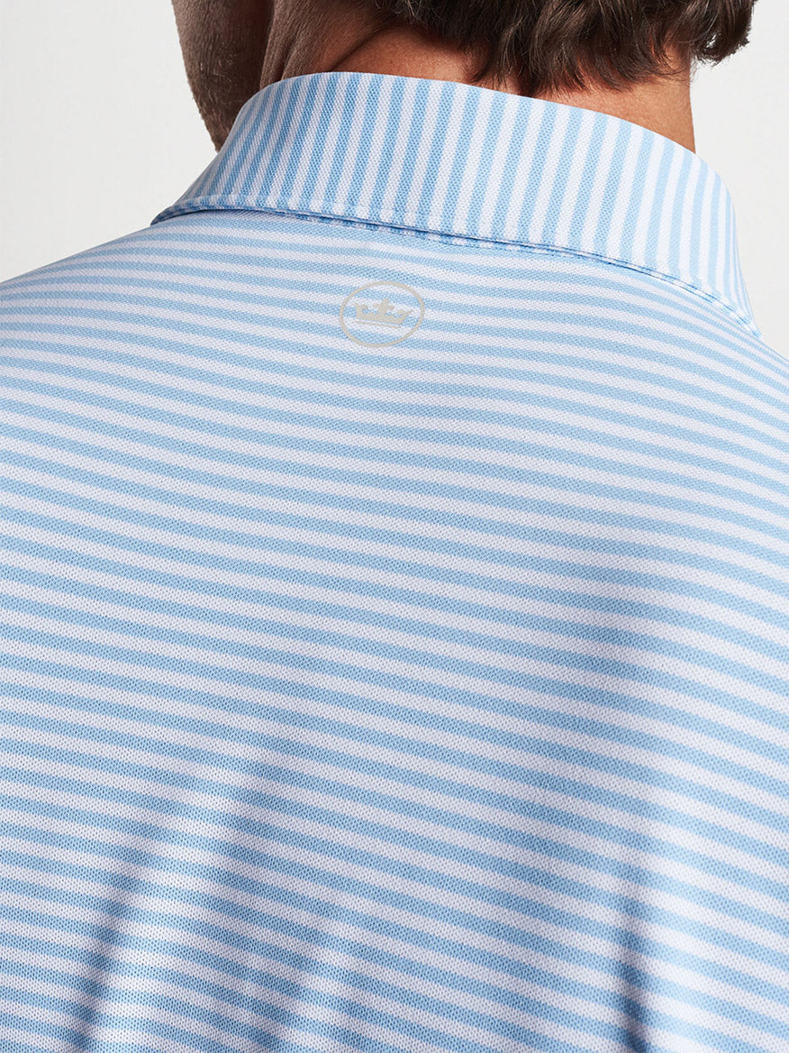 Close-up of a striped Peter Millar Mood Performance Mesh Polo in Blue Frost shirt collar with a logo detail.