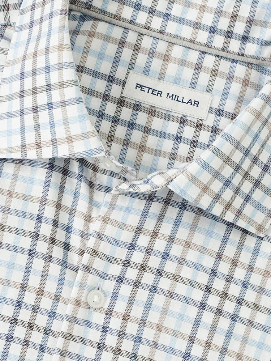 Close-up of the Peter Millar North Coast Crown Lite Cotton-Stretch Sport Shirt in Blue Haze, showcasing a blue, brown, and white plaid pattern, easy-care fabric, and the visible "Peter Millar" label.