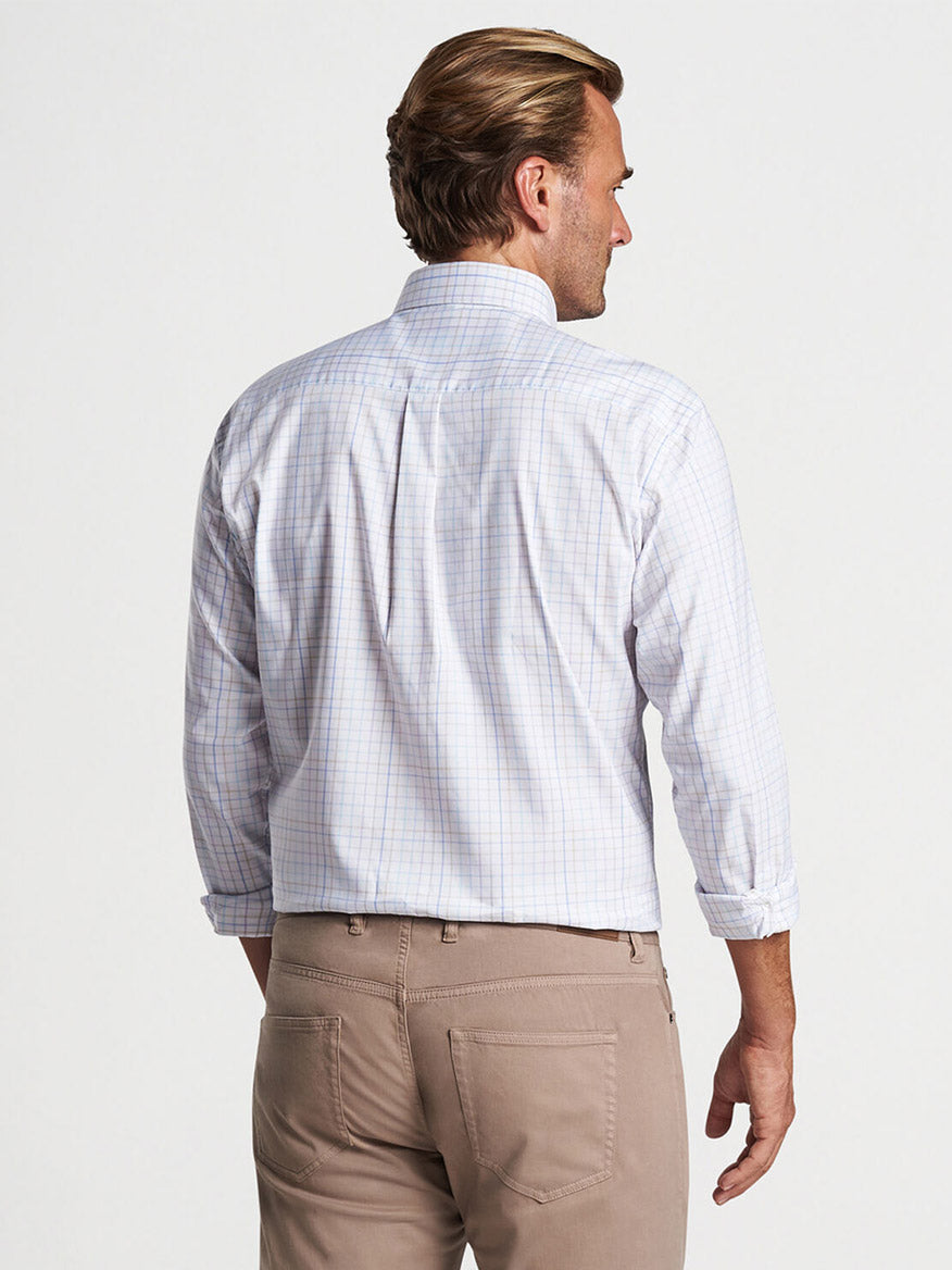 A man stands with his back to the camera, wearing a Peter Millar Patten Crown Lite Cotton-Stretch Sport Shirt in White and khaki pants.