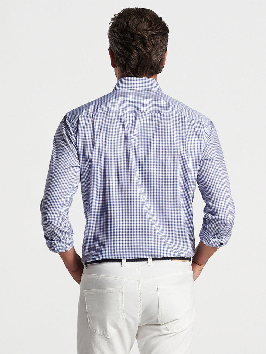 A man viewed from behind wearing a blue and white checked Peter Millar Renato Cotton Sport Shirt in Atlantic Blue and white pants, standing against a plain background.