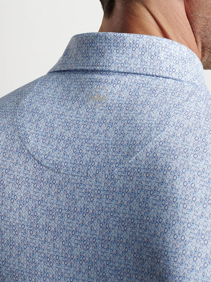 Close-up of a man wearing a Peter Millar Rhythm Performance Jersey Polo in White/Blue Pearl with a button-down collar and UPF 50+ sun protection.