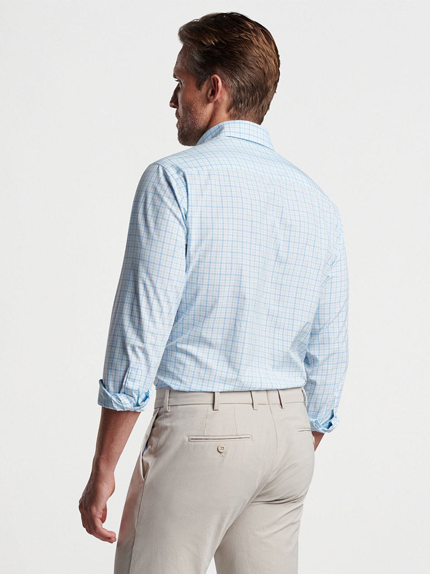 Man wearing a Peter Millar Rollins Performance Poplin Sport Shirt in Iced Aqua with beige trousers, facing away from the camera.