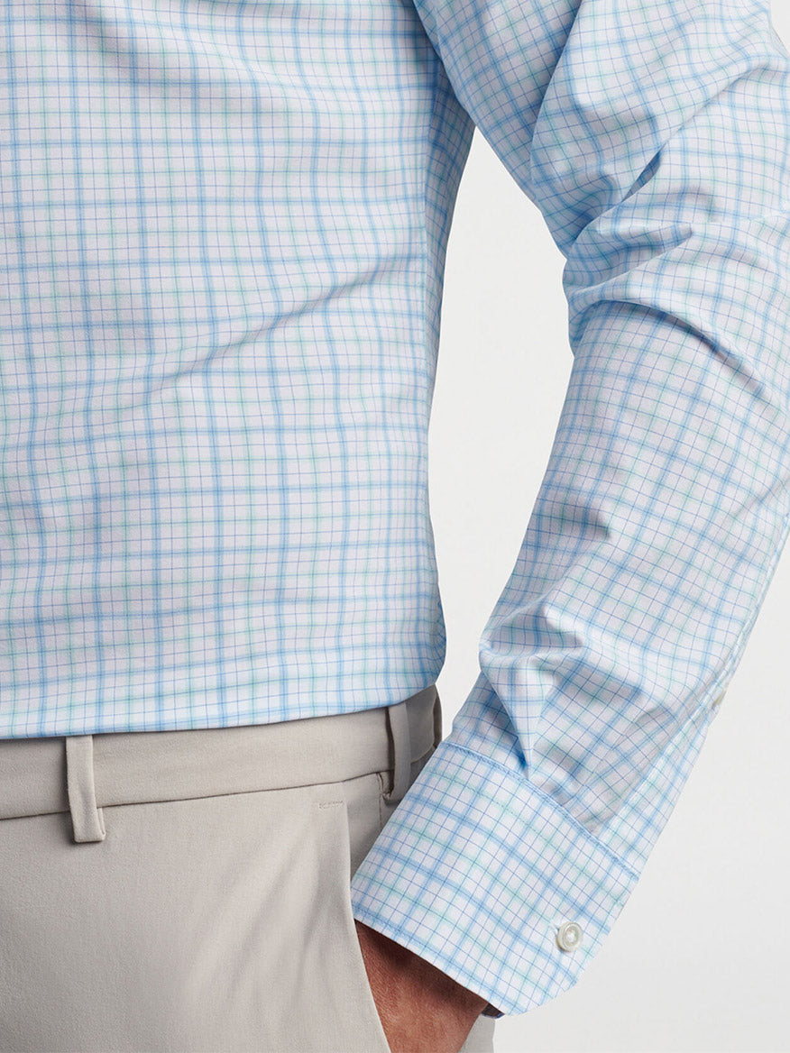 A close-up of a person wearing a Peter Millar Rollins Performance Poplin Sport Shirt in Iced Aqua with tailored-fit khaki trousers.