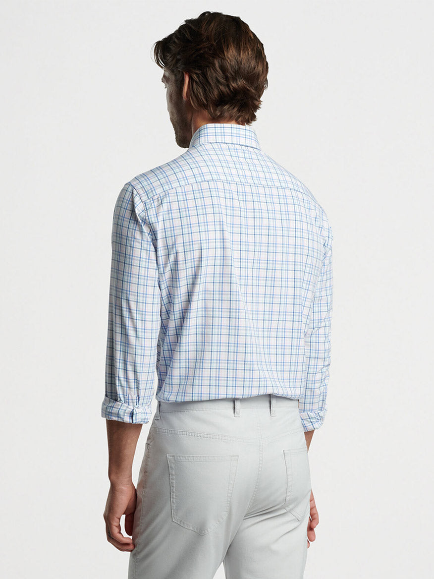 Man standing with his back to the camera wearing a Peter Millar Roxbury Performance Poplin Sport Shirt in Maritime and gray pants.