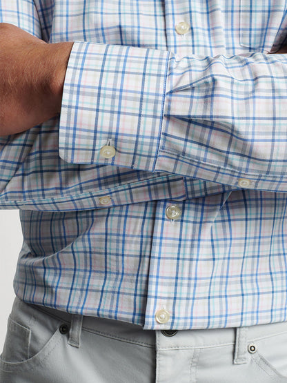 Close-up of a person wearing a Peter Millar Roxbury Performance Poplin Sport Shirt in Maritime with the focus on the buttoned cuff.