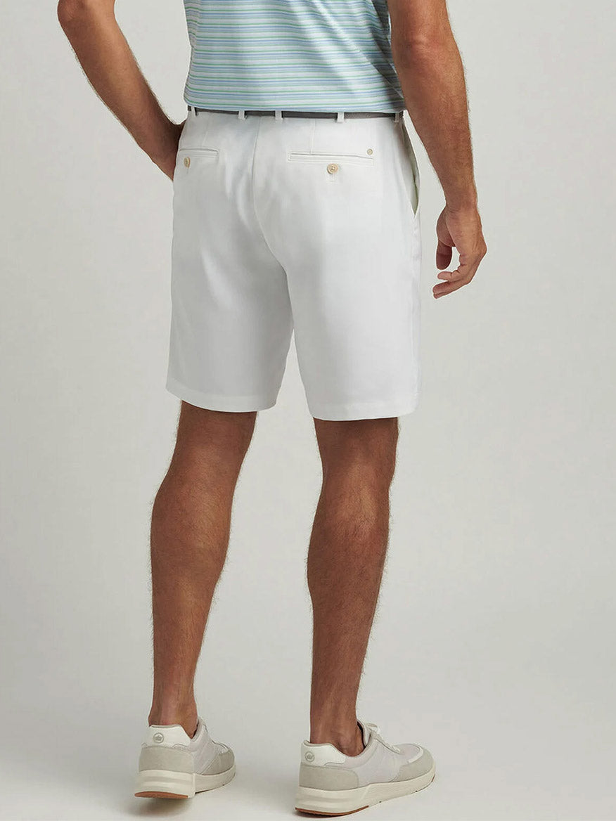 A man is seen from behind wearing a classic fit light blue striped shirt, Peter Millar Salem Performance Short in White, and white sneakers.