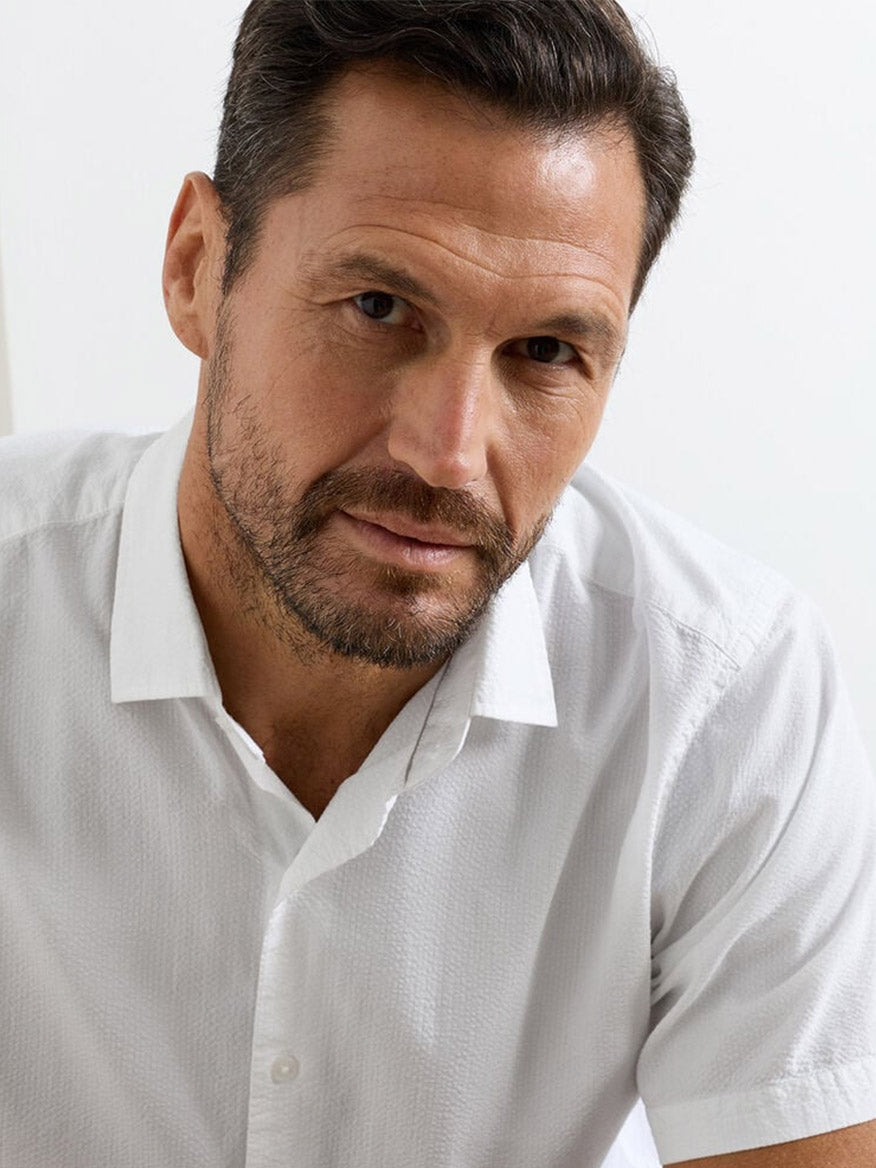 Man with short dark hair and beard wears the Peter Millar Seaward Cotton Lyocell Sport Shirt in White, looking directly at the camera with a neutral expression.