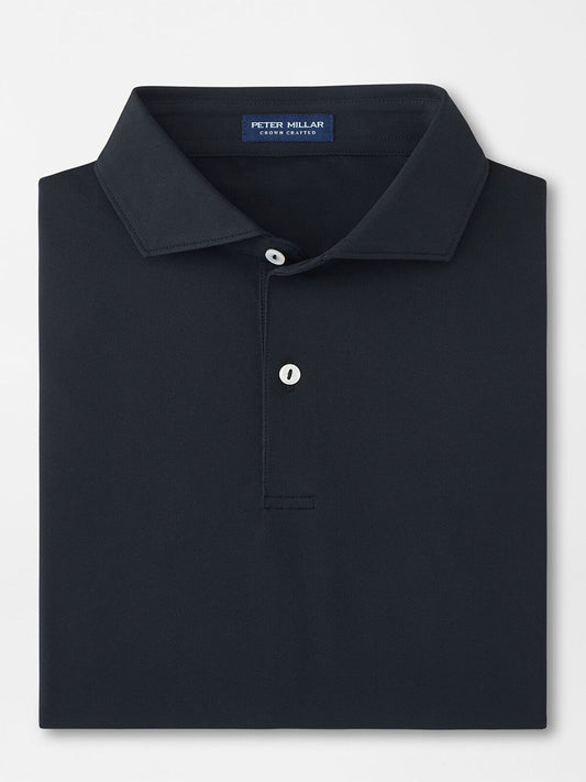 The Peter Millar Soul Performance Mesh Polo in Black is a well-folded, dark-colored shirt with a collar, featuring two mother-of-pearl buttons and an internal neck label.