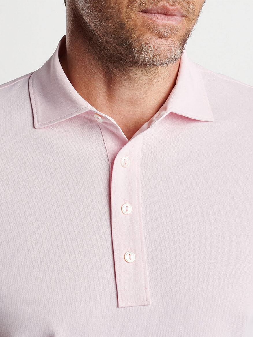 Close-up of a man wearing a Peter Millar Soul Performance Mesh Polo in Misty Rose, in a golf style.