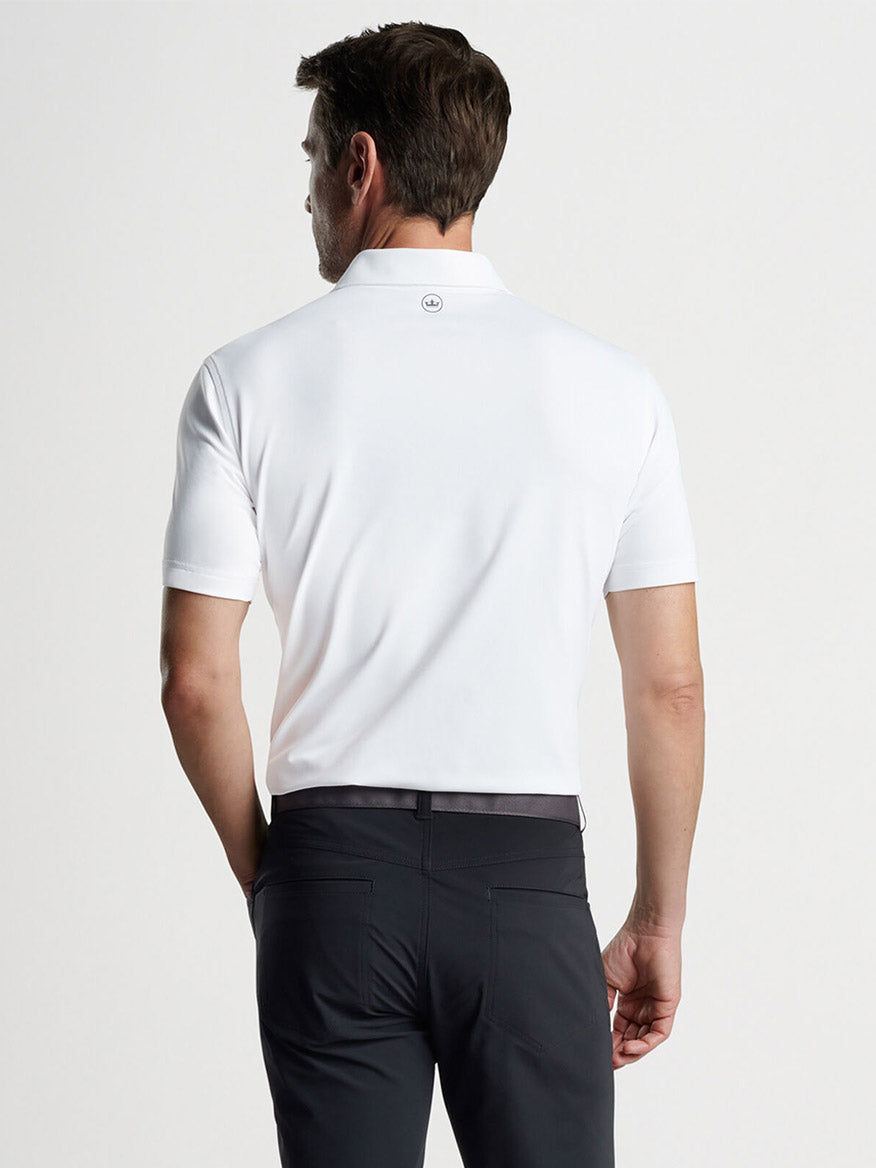 Man wearing a Peter Millar Soul Performance Mesh Polo in White with four-way stretch and black trousers against a neutral background.