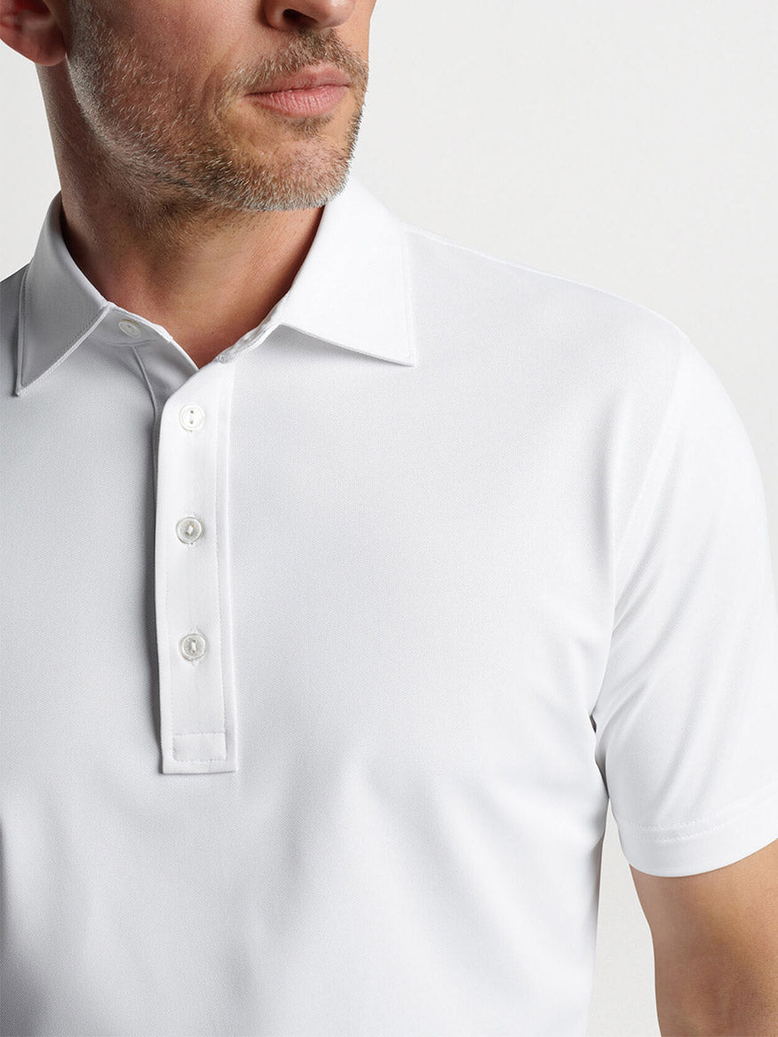 A man wearing a Peter Millar Soul Performance Mesh Polo in White with focus on the collar and button placket, featuring four-way stretch.