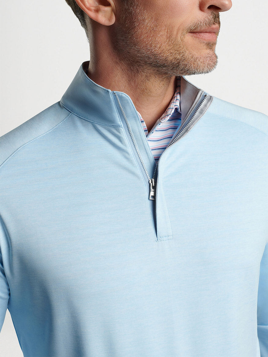 Man wearing a Peter Millar Stealth Performance Quarter-Zip in Blue Frost over a striped dress shirt.