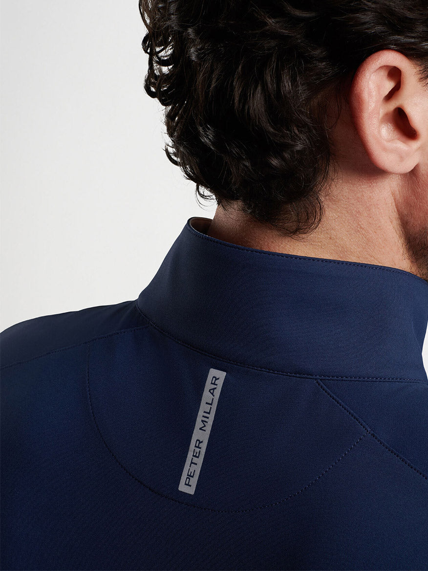 A close-up from behind of a person wearing a Peter Millar Stealth Performance Quarter-Zip in Navy with the "Peter Millar" label visible on the collar.