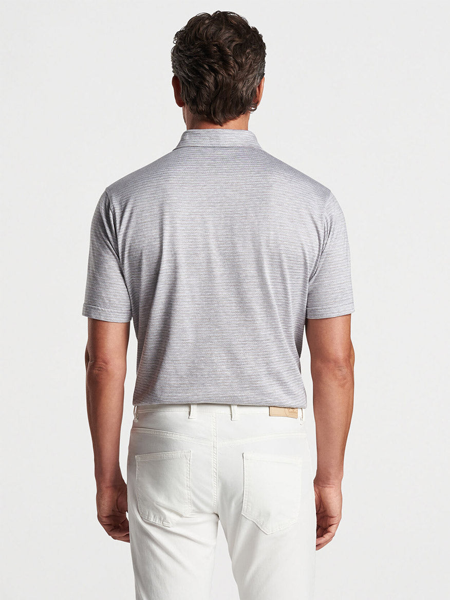 Man wearing a Peter Millar Tidewater Stripe Polo in British Grey and white pants viewed from behind.